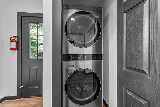 Laundry area featuring estacked washer and dryer, wood finished floors, and baseboards | Image 23
