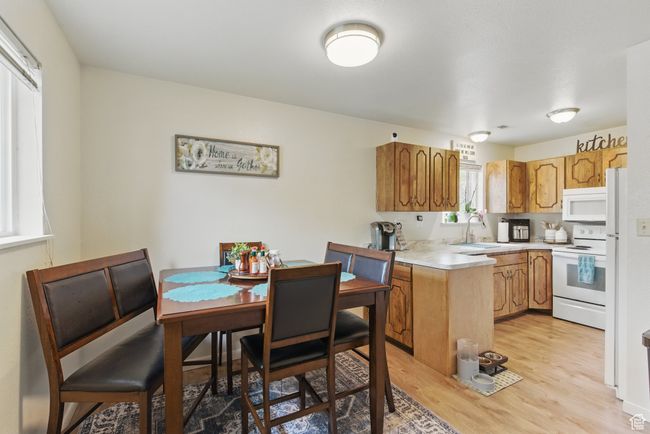 Kitchen featuring a sink, white appliances, light wood-type flooring, light countertops, and a peninsula | Image 24