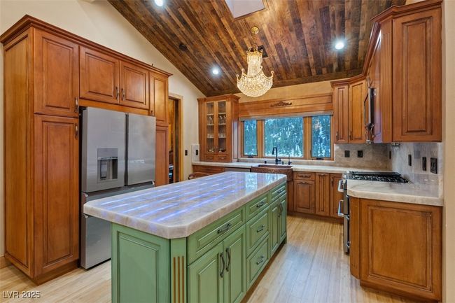Kitchen with wooden ceiling, a kitchen island, vaulted ceiling, appliances with stainless steel finishes, and decorative backsplash | Image 32