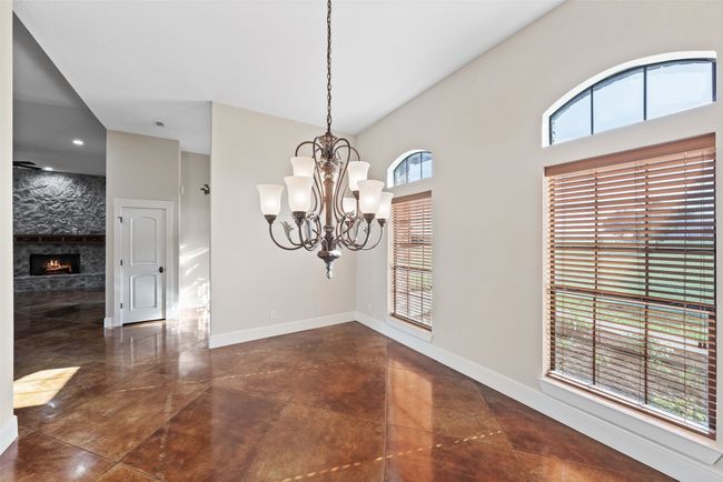 Unfurnished dining area featuring a chandelier, baseboards, a large fireplace, and a towering ceiling | Image 8