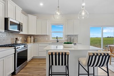 (Photo of a decorated model, actual homes finishes will vary) The stunning kitchen features a large center island, quartz countertops, LVP floors and stainless appliances! | Image 2