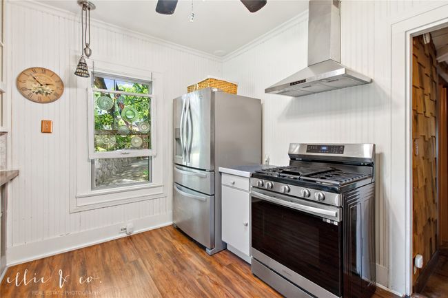 Kitchen with stainless steel appliances, wall chimney exhaust hood, ornamental molding, dark wood-type flooring, and baseboards | Image 17