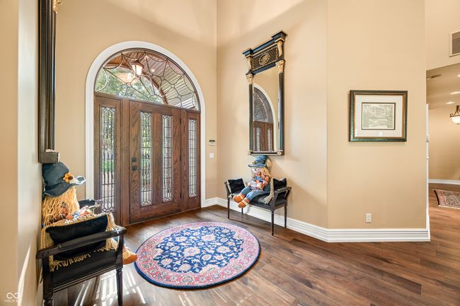 entrance foyer featuring a towering ceiling, wood finished floors, visible vents, and baseboards | Image 10