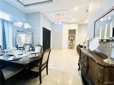 Dining room with a chandelier, a tray ceiling, and light tile patterned floors | Image 3