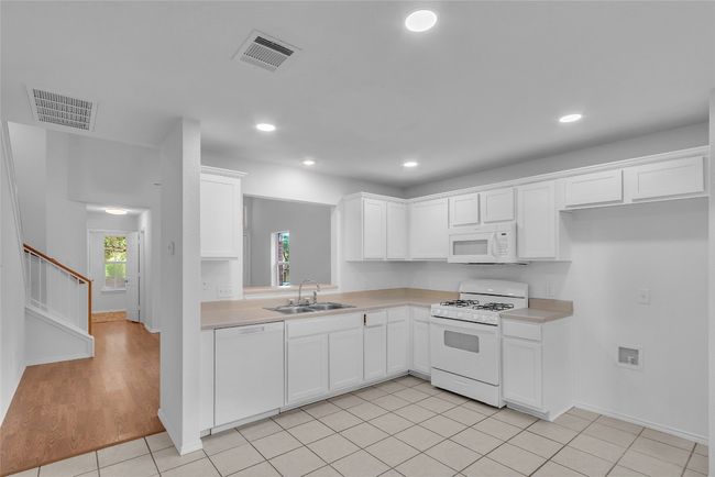 Kitchen featuring white appliances, light countertops, white cabinetry, light tile patterned floors, and recessed lighting | Image 12