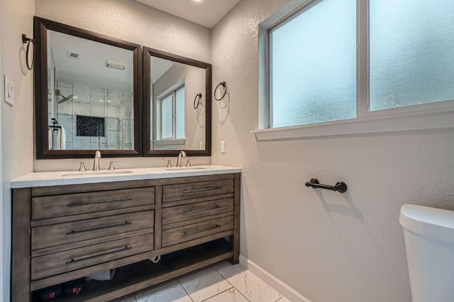 Full bath with marble finish flooring, double vanity, a textured wall, and a stall shower | Image 17