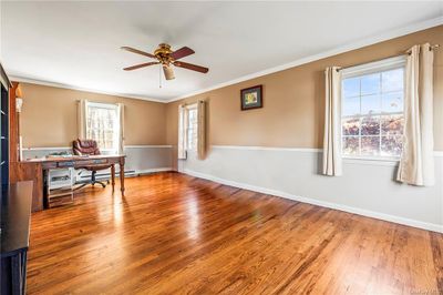 Office space featuring a baseboard radiator, hardwood / wood-style floors, ceiling fan, and crown molding | Image 3