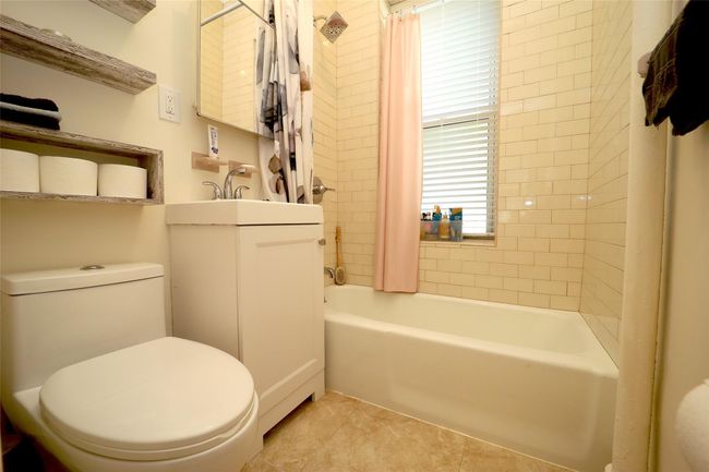 Bathroom with toilet, tile patterned floors, shower / bathtub combination with curtain, and vanity | Image 12