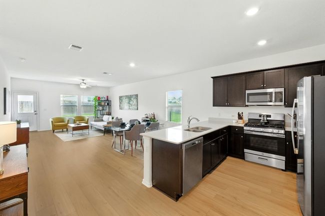 Kitchen featuring stainless steel appliances, open floor plan, light wood-type flooring, dark brown cabinetry, and recessed lighting | Image 12