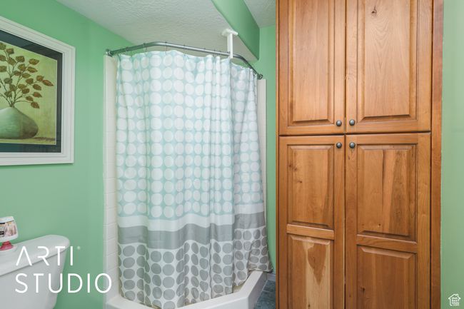 Full bath with a textured ceiling, toilet, and shower / tub combo | Image 18