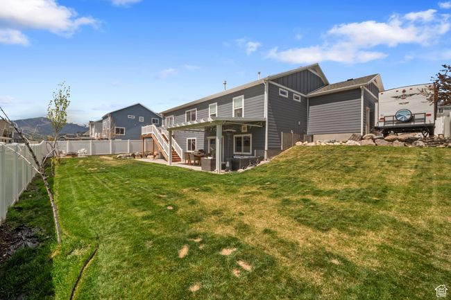 Back of house featuring board and batten siding, a patio, a lawn, stairway, and a fenced backyard | Image 21