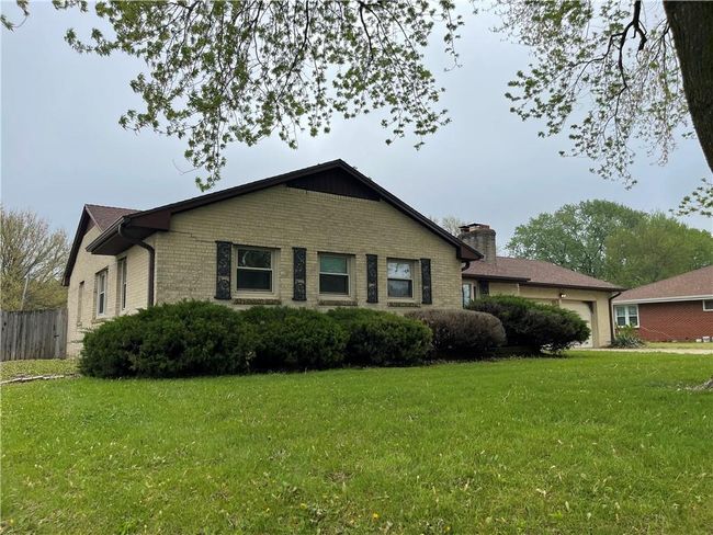 View of side of home featuring a lawn, a chimney, an attached garage, and brick siding | Image 4