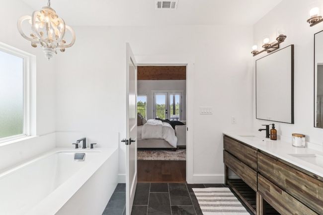 Ensuite bathroom with double vanity, tile patterned flooring, a garden tub, and a chandelier | Image 23
