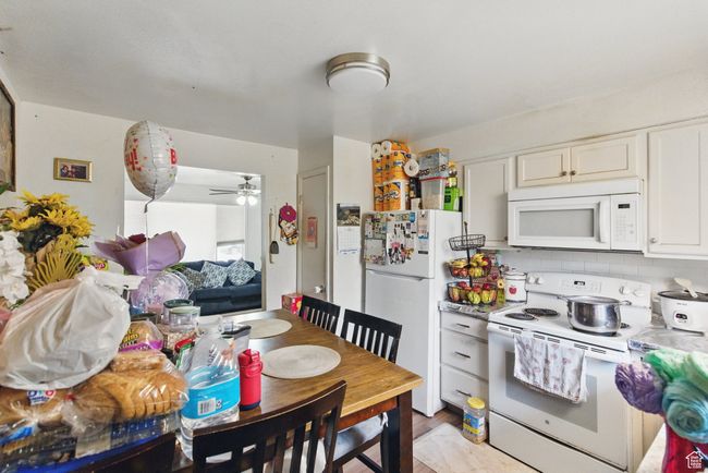 Kitchen featuring decorative backsplash, white appliances, ceiling fan, light countertops, and white cabinets | Image 23