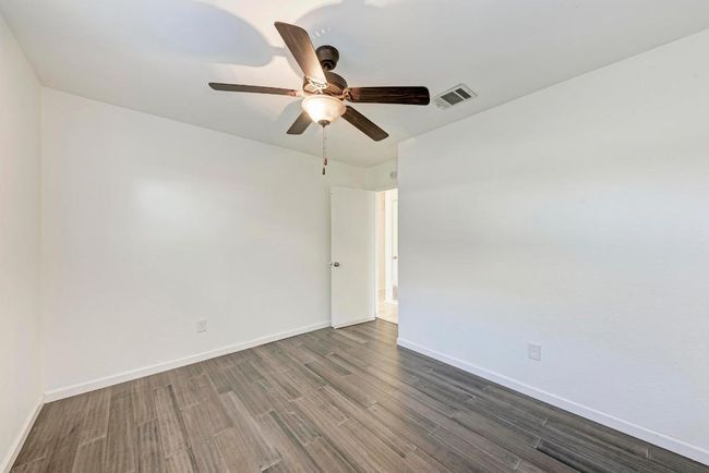 Spare room with visible vents, baseboards, ceiling fan, and dark wood-style flooring | Image 25