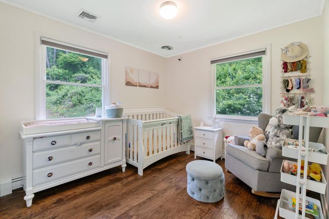 Bedroom featuring ornamental molding, multiple windows, dark wood-style flooring, and a nursery area | Image 27