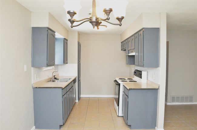 Kitchen featuring a sink, visible vents, gray cabinetry, white electric stove, and a notable chandelier | Image 11