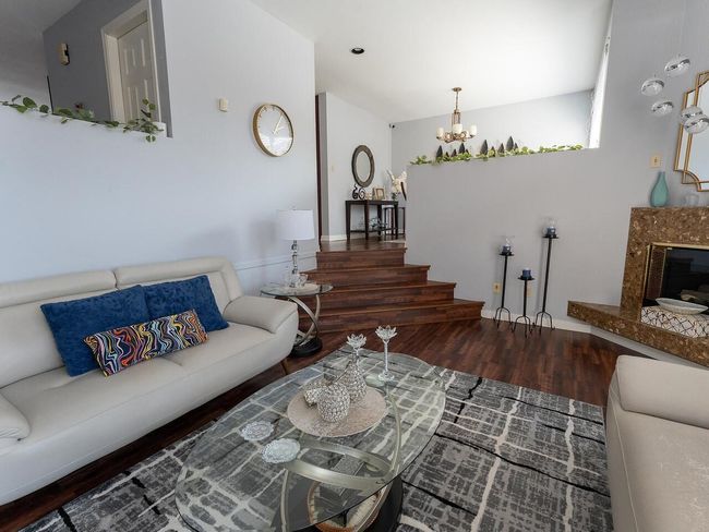 Living area with wood finished floors, stairway, and an inviting chandelier | Image 7