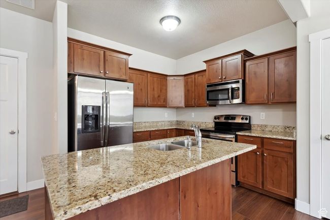 Kitchen featuring stainless steel appliances, a sink, dark wood-style flooring, and light stone countertops | Image 12