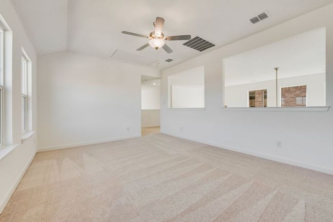 Empty room featuring a ceiling fan, carpet flooring, attic access, and lofted ceiling | Image 5