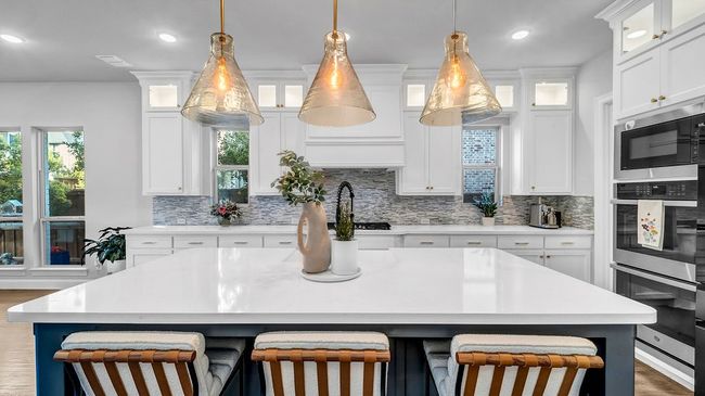 Kitchen featuring stainless steel appliances, light countertops, a breakfast bar area, and backsplash | Image 4