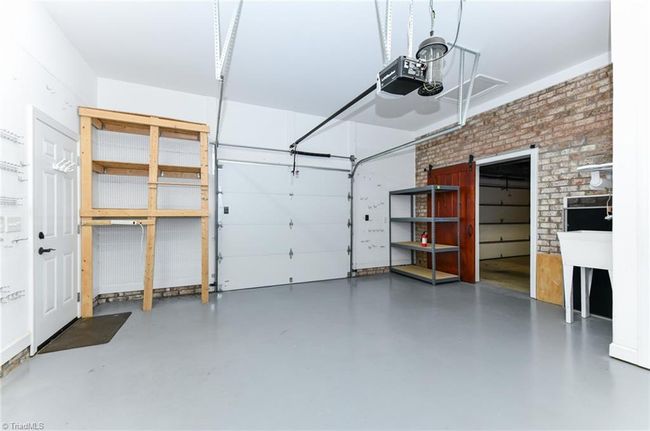3rd car garage or workshop has a window unit for AC and a water closet bathroom. Shelving, utility sink and barn door included. | Image 28