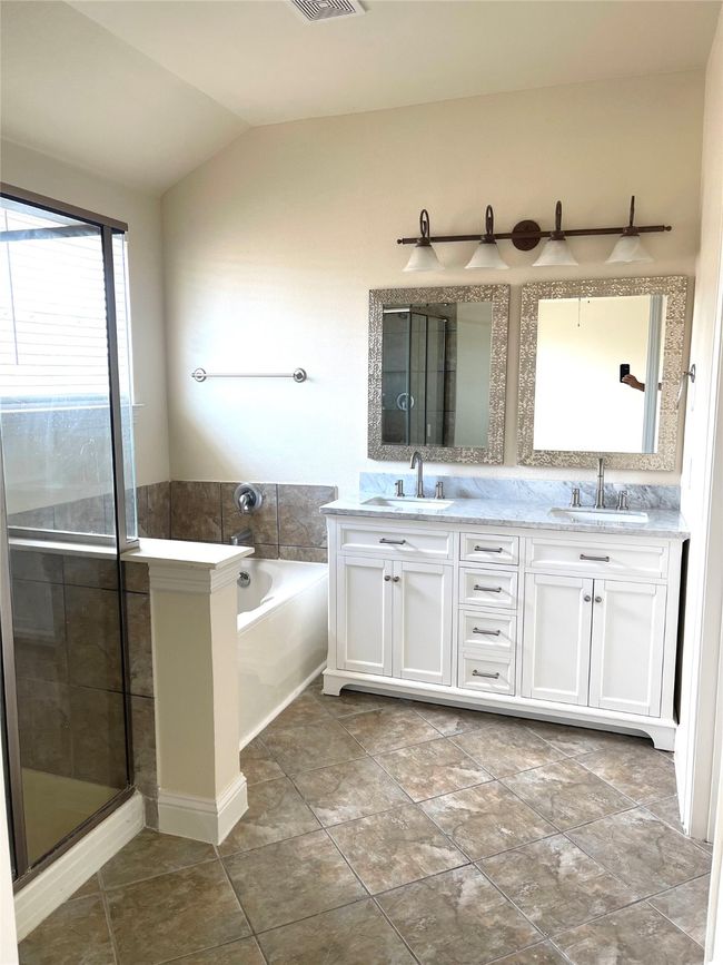 Bathroom featuring a bath, double vanity, vaulted ceiling, and a shower with door | Image 15