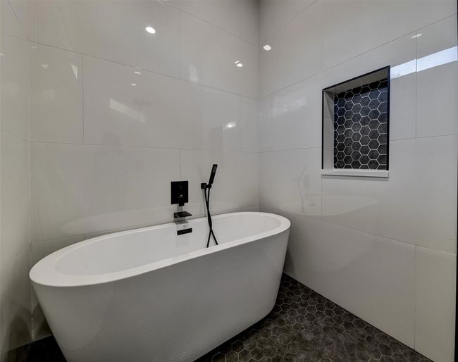 Bathroom featuring tile patterned flooring, a tub to relax in, and tile walls | Image 12
