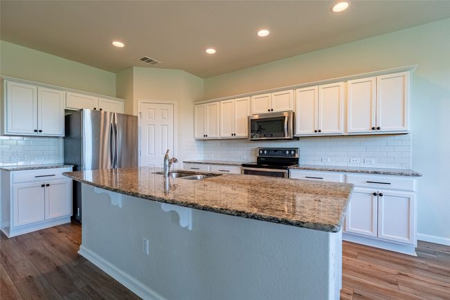Kitchen with decorative backsplash, wood finished floors, electric range, stainless steel microwave, and recessed lighting | Image 7