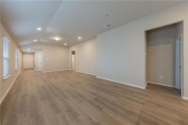 Empty room with wood finished floors, recessed lighting, lofted ceiling, and baseboards | Image 5