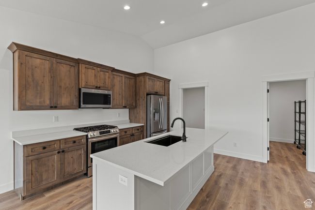 Kitchen featuring appliances with stainless steel finishes, a sink, high vaulted ceiling, a kitchen island with sink, and light wood-style floors | Image 7