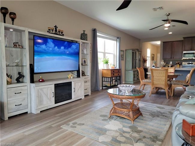Living area with ceiling fan, light wood finished floors, and visible vents | Image 20