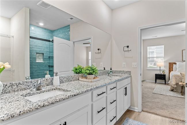 Ensuite bathroom featuring a shower stall, double vanity, wood finished floors, and baseboards | Image 33