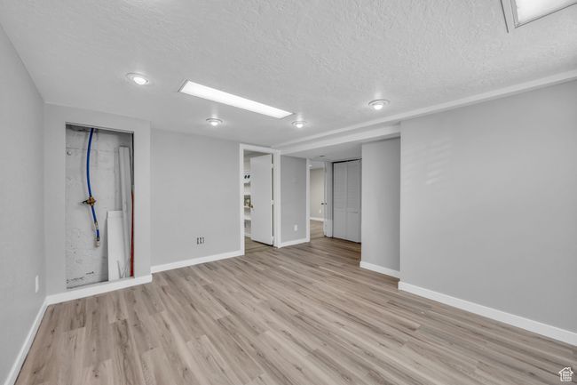 Below grade area with a textured ceiling, baseboards, and light wood-type flooring | Image 19