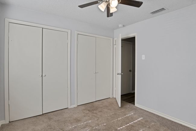 Unfurnished bedroom with visible vents, two closets, a textured ceiling, carpet floors, and baseboards | Image 21