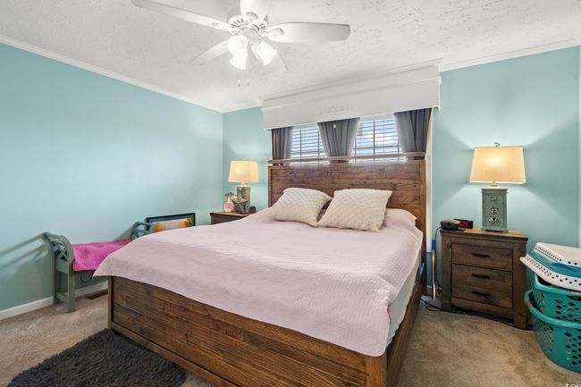 Carpeted bedroom with crown molding, a textured ceiling, and a ceiling fan | Image 12