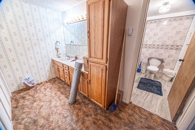 Bathroom featuring vanity, tile walls, toilet, and a textured ceiling | Image 37