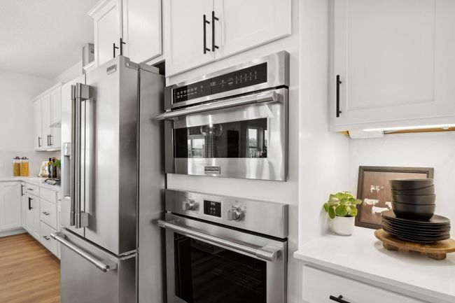 (Photo of a decorated model, actual homes finishes will vary) This stunning gourmet kitchen features a large center island, quartz countertops, LVP floors, stainless appliances and more! | Image 4