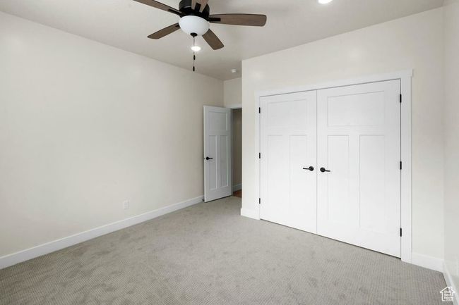 Unfurnished bedroom featuring a ceiling fan, light carpet, a closet, and baseboards | Image 20