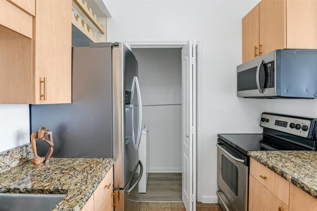 Kitchen featuring stainless steel appliances, stacked washing machine and dryer, light brown cabinets, and stone countertops | Image 15