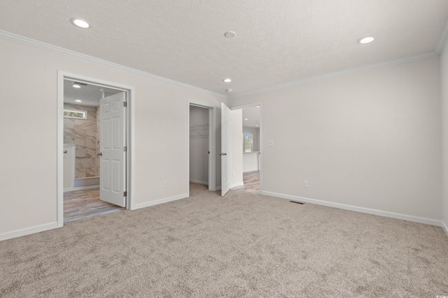 Unfurnished bedroom featuring crown molding, carpet, and a textured ceiling | Image 15