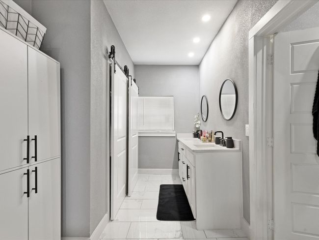 Full bath with vanity, a textured wall, marble look tiles, recessed lighting, and baseboards | Image 12