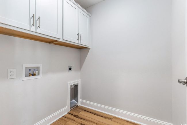 Washroom with hookup for an electric dryer, cabinet space, light wood-style floors, and hookup for a washing machine | Image 26