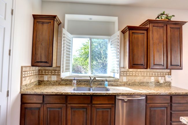 Kitchen with tasteful backsplash, light stone counters, dishwasher, and a sink | Image 20