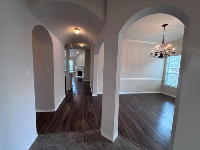 Corridor with dark wood-type flooring, arched walkways, and a chandelier | Image 4
