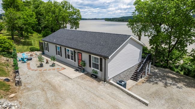 view of front of house featuring a water view, stairway, a shingled roof, central air condition unit, and a patio area | Image 77