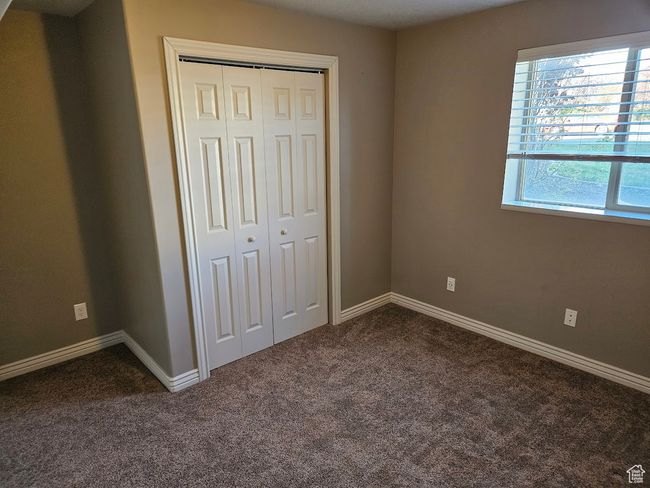 Unfurnished bedroom with dark colored carpet, baseboards, and a closet | Image 33