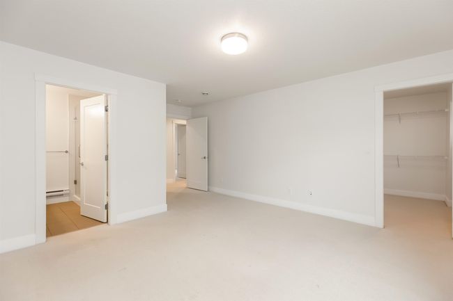 Unfurnished bedroom featuring a baseboard radiator, carpet, baseboards, and a walk in closet | Image 15