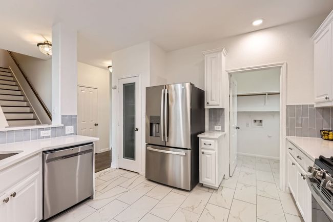 Kitchen with appliances with stainless steel finishes, light marble finish floors, light countertops, white cabinets, and recessed lighting | Image 7