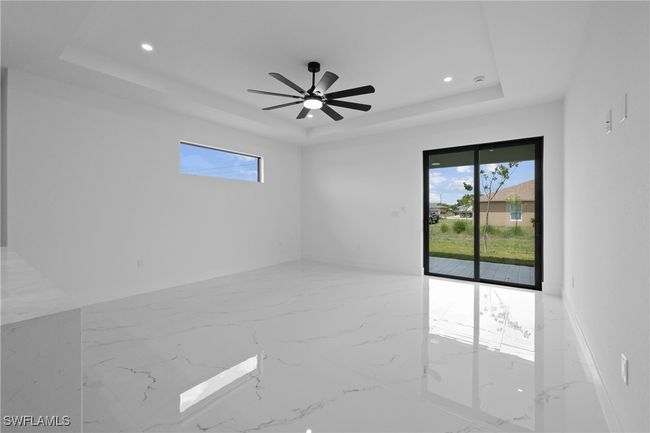 Unfurnished room featuring a tray ceiling, plenty of natural light, recessed lighting, and marble tiled flooring | Image 13